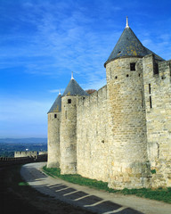 Fototapeta na wymiar France, Carcassonne. Shadows of the crenelatted walls shade the pathway under the towers at La Cite in Carcassonne, Dept. Aude, France.