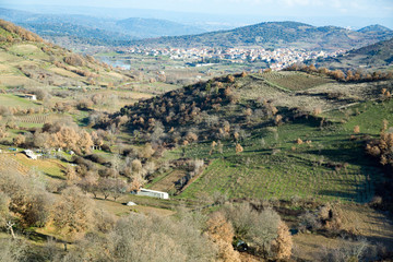 Fototapeta na wymiar Italy, Sardinia, Ovodda. Looking down at farms and rolling hills with Ovodda in the background.