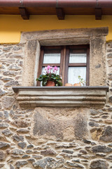 Fototapeta na wymiar Italy, Sardinia, Santu Lussurgiu. Plants sitting the windowsill of a stone walled building.
