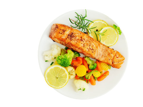Grilled salmon fillet with vegetables, lemon and rosemary over white plate isolated, top view, overhead.