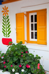 Greece, Mykonos, Orange-yellow shuttered window, geraniums.