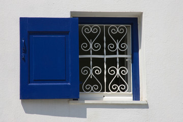 Greece, Mykonos, Hora. Open window with blue shutter and iron grill contrast with white wall.