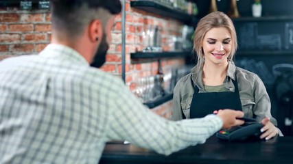 Hipster man buying take away coffee talking with female barista at cafe back view