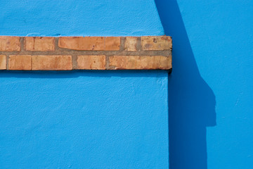Italy, Burano. Close-up of blue stucco exterior of chimney and colored brick.