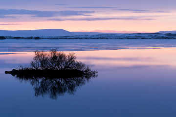 North Iceland, near Lake Myvatn, Reykjahlio. A colorful sunset is reflected in a tundra pond.