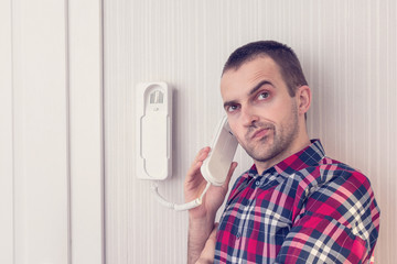 Man with intercom or phone land line, man is dissatisfied with the interlocutor, portrait, close up, toned