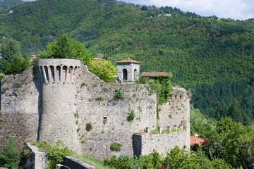 Fototapeta premium Castelnuovo di Garfagnana, Tuscany, Italy - A rundown stone castle set in a valley.