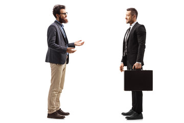 Bearded man talking to a young man in a suit holding a briefcase