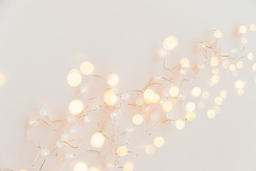 Warm light garlands on pink background, festive decorations. Flat lay, top view