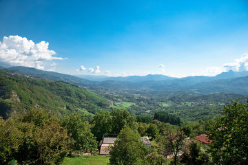 Naklejka na ściany i meble Castelnuovo di Garfagnana, Tuscany, Italy - High angle view of a green rural valley with homes.