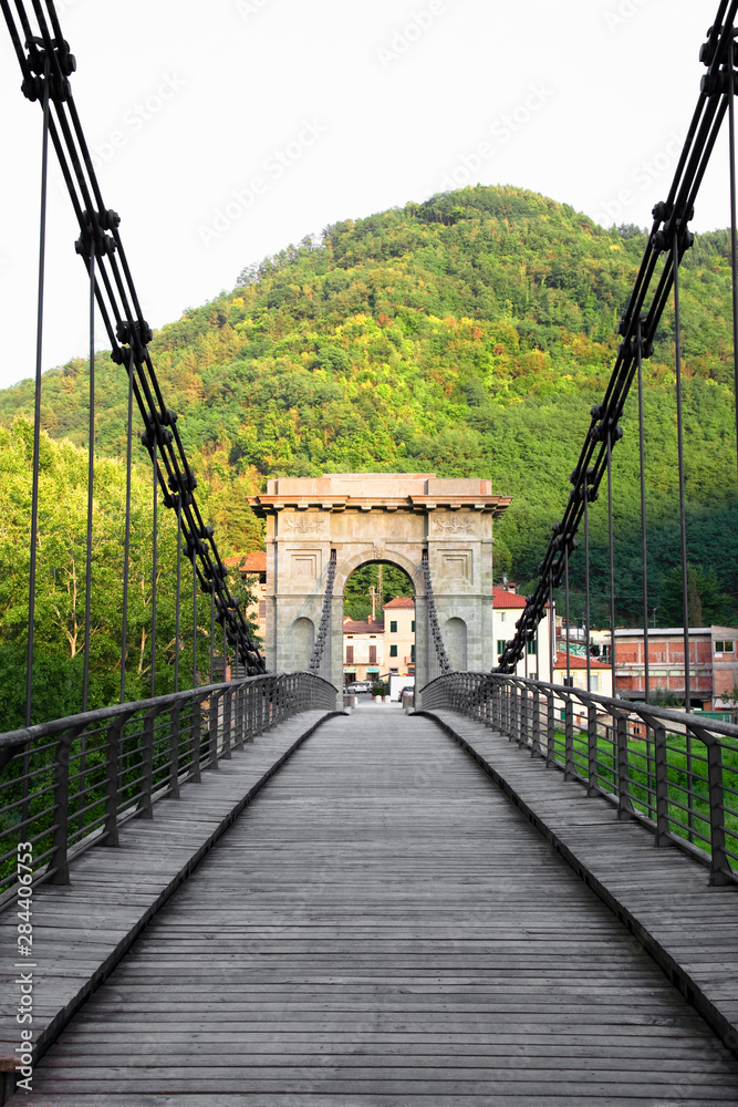 Poster Bagni di Lucca, Tuscany, Italy - An old bridge with an arch at the exit. A hillside is viewable in the background.