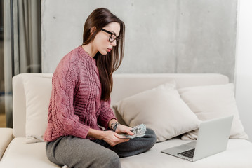 woman earning money at home on a couch with laptop