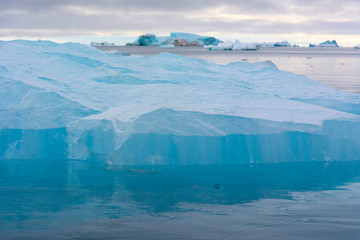 Norway. Svalbard. Nordaustlandet Island. Brasvelbreen. Turquoise ice bergs in the calm water.