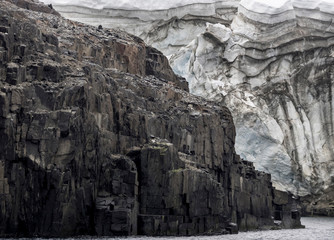 Fototapeta na wymiar Arctic Ocean, Norway, Svalbard. Glacier next to cliff.