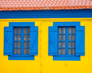 Fototapeta na wymiar Portugal, Aveiro. Yellow house with blue shutters, windows and doors.