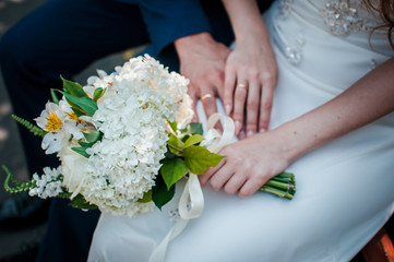 Obraz na płótnie Canvas Bride and groom hands with flower bouquet in the hands