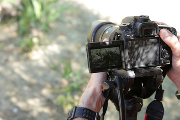  digital camera in the hand of a photographer or videographer with a monopod. Outdoors.