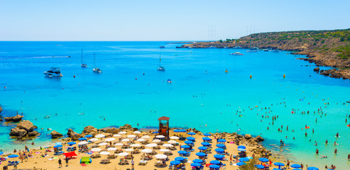  blue sea with clear water, mountains, yachts and the beach on the panorama of Konnos Bay Cyprus