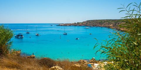  blue sea with clear water, mountains, yachts and the beach on the panorama of Konnos Bay Cyprus