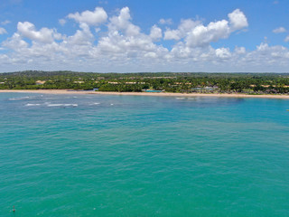 Aerial view of tropical white sand beach, palm trees  and turquoise clear sea water in Praia do Forte, Bahia, Brazil. Travel tropical destination in Brazil