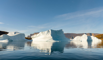 Fototapeta na wymiar Landscape with steep yellow cliffs and icebergs in the Uummannaq fjord system, northwest Greenland.