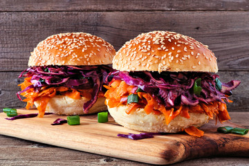 Pulled carrot meatless burgers with red cabbage slaw against a wood background. Healthy eating,...