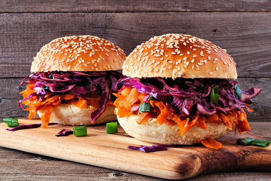 Pulled carrot meatless burgers with red cabbage slaw against a wood background. Healthy eating, plant-based meat substitute concept.