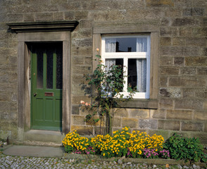 Fototapeta na wymiar England, Grassington. A green door is the perfect companion to a white paned window in Grassington, Yorkshire Dales NP, England.