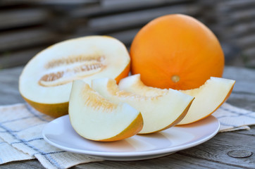 Ripe sweet melon slices on a white plate, closeup. Shallow depth of field, selective focus