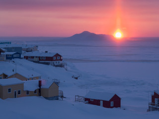 Sunset over icefjord and town. Ilulissat at the shore of Disko Bay, center for tourism, administration and economy. The icefjord nearby is listed as UNESCO World Heritage Site. Greenland, Denmark.