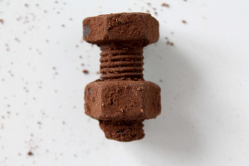 Rusty bolt and nut made of chocolate isolated on white background. Chocolate chip scattered on smooth surface. Mechanic gearing background. Father's day card obects