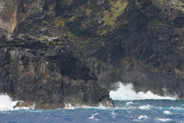 Pitcairn Islands, Pitcairn Island. Coastal view of the rugged volcanic shore of Pitcairn. Rough seas, that are common in the area, crashing on rocky shore.