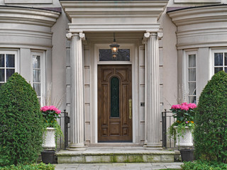 front of elegantly landscaped house with stone column portico over wooden front door