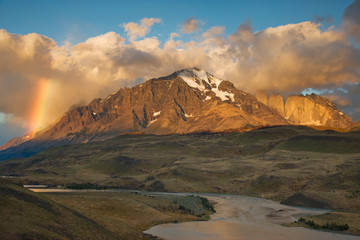 Chile, Torres del Paine National Park. Sunrise rainbow lights mountain with the Rio Paine in the foreground. 