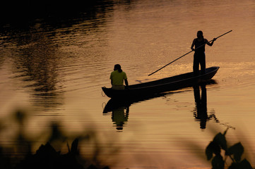 Quichua Indians poling dugout canoe on jungle lake. Amazon Rain Forest. Ecuador. South America - obrazy, fototapety, plakaty
