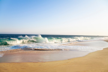 Cabo San Lucas, Baja California Sur, Mexico - Waves from the ocean surf are breaking onto a sandy beach.