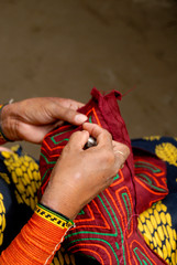 Panama, San Blas Islands (aka Kuna Yala). Colorful hand stitched mola. Close up of sewing, also showing typical beaded armband worn by Kuna women.