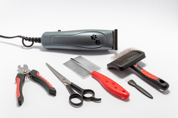 Pets care kit: pet trimmer, metal brush, metal comb, scissors, claw cutters, small brush for cleaning. Isolated on white background.