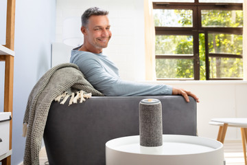 Man Listening To Wireless Speaker On Furniture