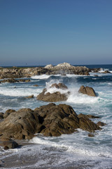 Fototapeta na wymiar Waves, blue water and rocks along Monterey Peninsula, California coast