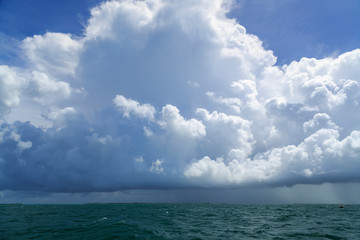 Afternoon thunderstorm above the Lower Florida Keys with bright afternoon sunlight and green waters of Florida Bay in the foreground.