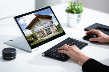 Woman selecting new house on laptop at home - obrazy, fototapety, plakaty