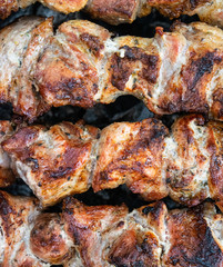 Frying pork on a skewer over a brazier. Turning meat over coals. Appetizing shish kebab.