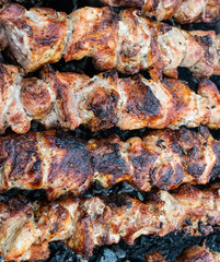 Frying pork on a skewer over a brazier. Turning meat over coals. Appetizing shish kebab.