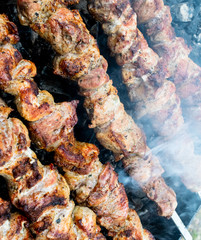 Frying pork on a skewer over a brazier. Turning meat over coals. Appetizing shish kebab.
