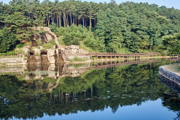 A view of rocky passage and wooden bridge reflected upon the waters of Ulrimji Reservoir in Jechun, South Korea.