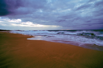 USA, Hawaii, Molokai. Under clouds of grey clouds, frothy surf rushes the shore on Molokai, Hawaii.
