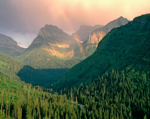 USA, Montana, Glacier NP. A rainbow graces the mountains seen from Going-to-the-Sun Highway,...