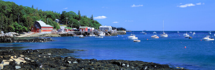 USA, Maine, Tenants Harbor. The bright blue waters of Tenants Harbor contrast the red shoreline...