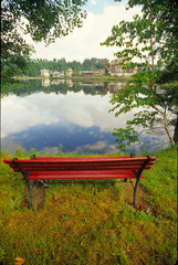 Obraz premium Red bench overlooking Flower Lake in the town of Saranac Lake in the Adirondacks northeastern New York